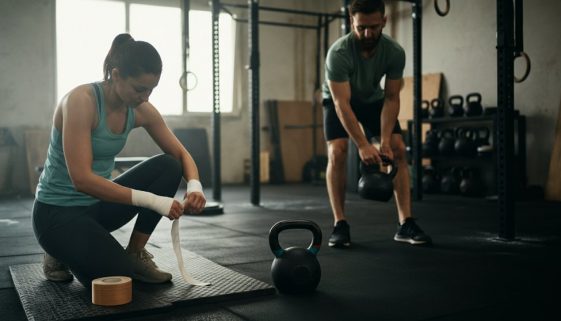 Ein Mann und eine Frau bereiten konzentriert ihre Ausrüstung für Crosstraining in einem Home-Gym vor.