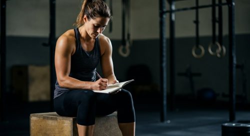 Fokussierte Athletin in einer Cross-Training-Box, die ihren Crosstraining Trainingsplan erstellt.