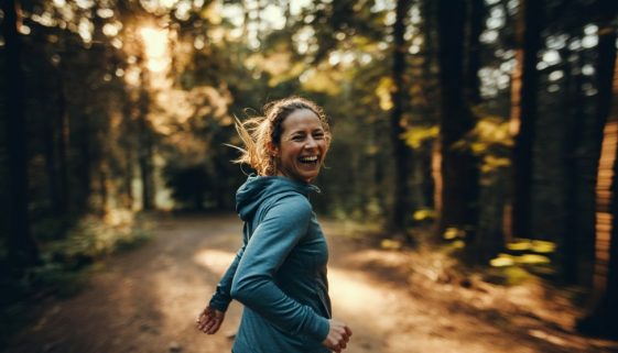 Eine Läuferin hat sichtlich Spaß bei ihrem Fartlek Training auf einem Waldweg.