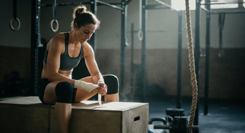 Eine Athletin sitzt in einer CrossFit-Box und bereitet sich konzentriert auf die Girl WODs vor.