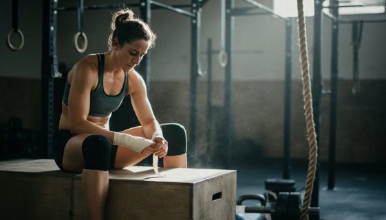 Eine Athletin sitzt in einer CrossFit-Box und bereitet sich konzentriert auf die Girl WODs vor.