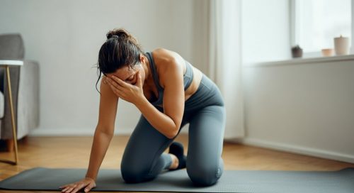 Eine Frau macht nach anstrengenden HIIT Core Übungen eine kurze Pause auf ihrer Matte und blickt zufrieden. Eine Frau macht nach anstrengenden HIIT Core Übungen eine kurze Pause auf ihrer Matte und blickt zufrieden.