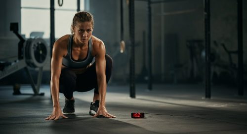Fokussierte Athletin blickt auf eine Stoppuhr, um ihr Training nach strukturierten HIIT Protokollen zu starten. Fokussierte Athletin blickt auf eine Stoppuhr, um ihr Training nach strukturierten HIIT Protokollen zu starten.
