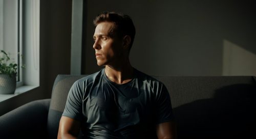 Eine sportliche Person entspannt nach dem Training auf dem Sofa, was den Nachbrenneffekt symbolisiert.