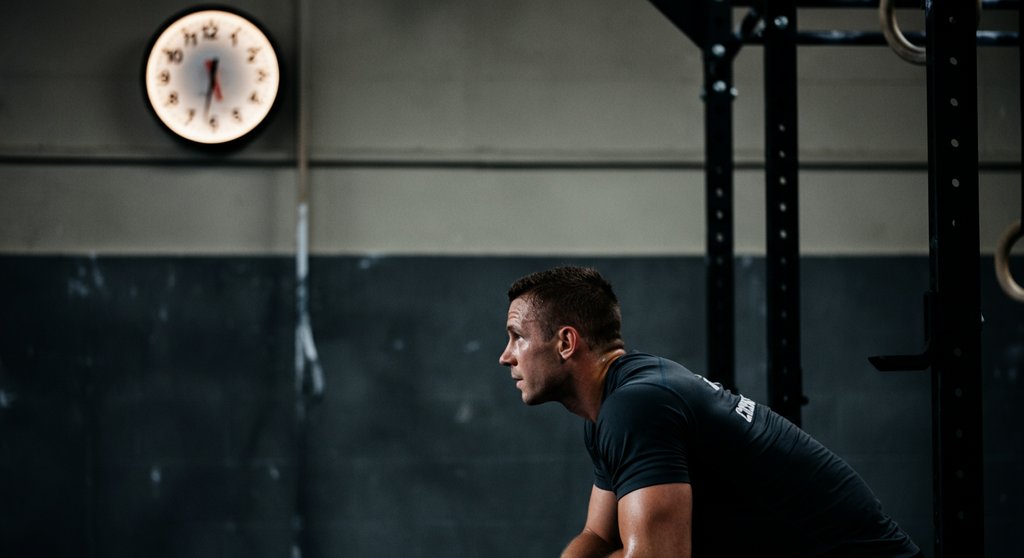 Athlet macht eine kurze Pause während eines EMOM Crosstraining WOD und schaut auf die Uhr.
