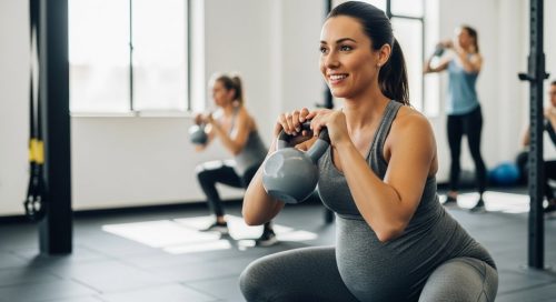 Eine schwangere Frau führt sicher eine Kniebeuge beim Crosstraining aus.