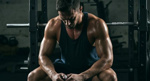 Ein athletischer Mann pausiert nach dem Training gemäß seinem Powerbuilding Trainingsplan in einem Gym. Ein athletischer Mann pausiert nach dem Training gemäß seinem Powerbuilding Trainingsplan in einem Gym.