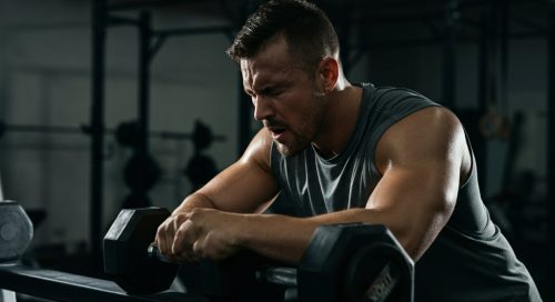 Ein Athlet macht eine kurze Pause während seines intensiven Rest-Pause Trainings im Fitnessstudio. Ein Athlet macht eine kurze Pause während seines intensiven Rest-Pause Trainings im Fitnessstudio.