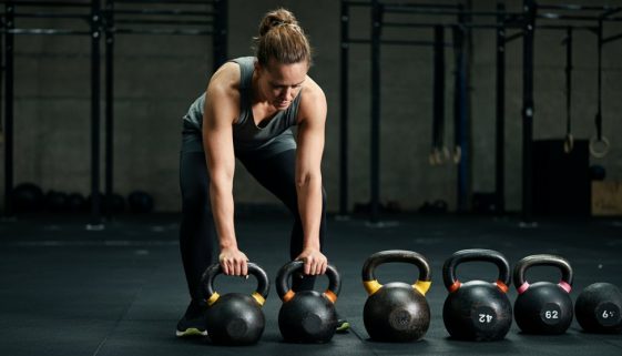 Ein Athlet wählt überlegt eine Kettlebell aus als Beispiel für ein smartes, scaled Crosstraining.