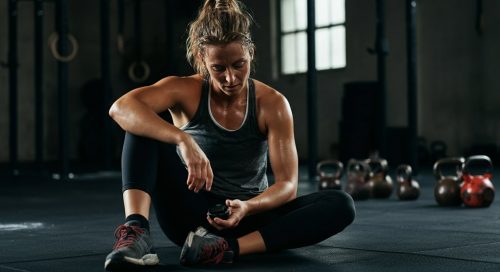 Athletin prüft nach dem Training die WOD Dauer auf ihrer Stoppuhr, um die Effektivität zu bewerten.